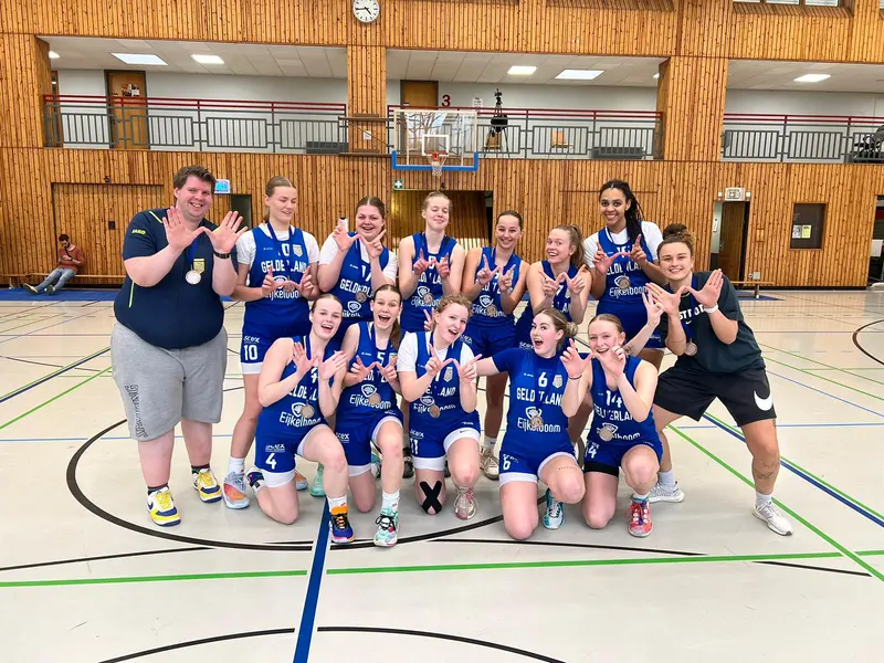 The United Basketball women’s team with medals in a wood-panelled sports hall in Berlin.