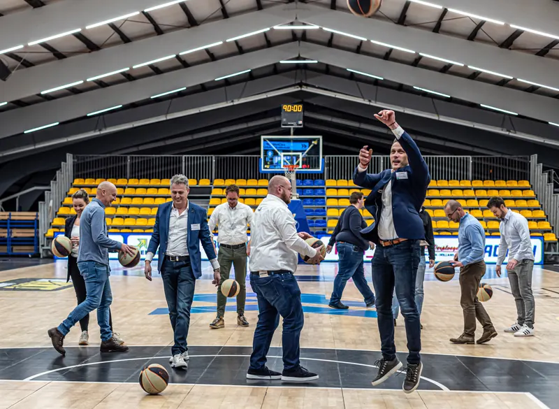 Business guests in suits and jeans take part in a shootout on the court at De Kooi