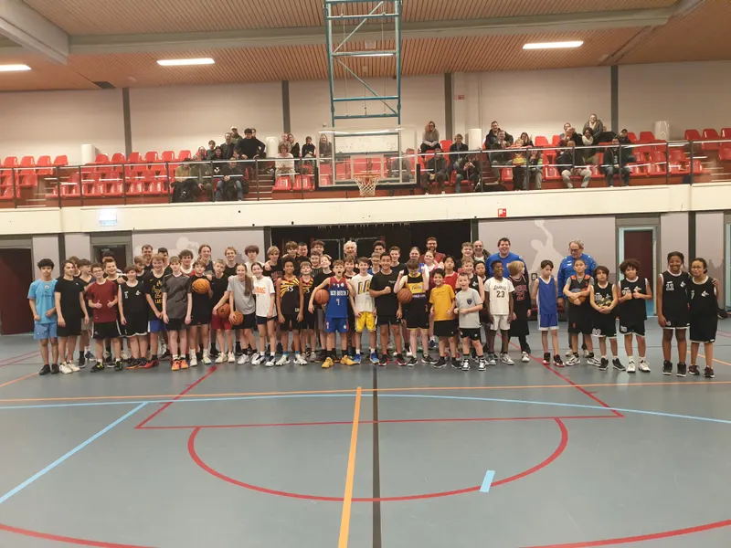 Groepsfoto van tientallen jeugdspelers na een clinic in een sporthal