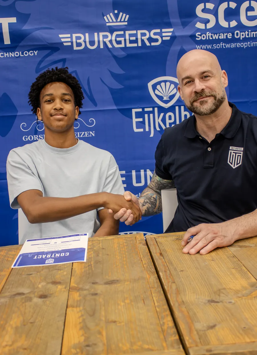 Een Academy-speler tekent zijn contract, samen met een staflid van GET United
